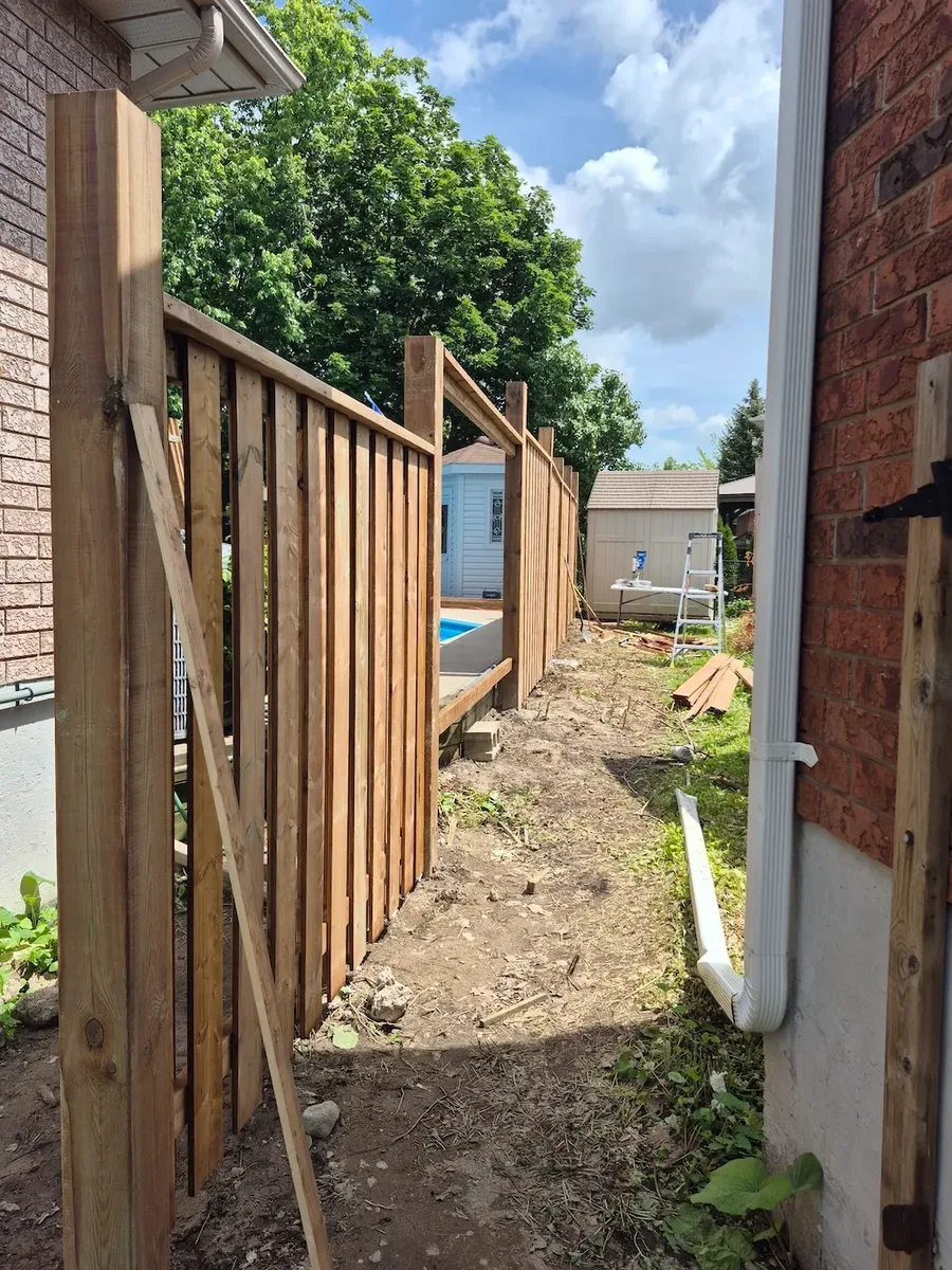 Pressure-treated fence boards being installed beside a pool in Barrie